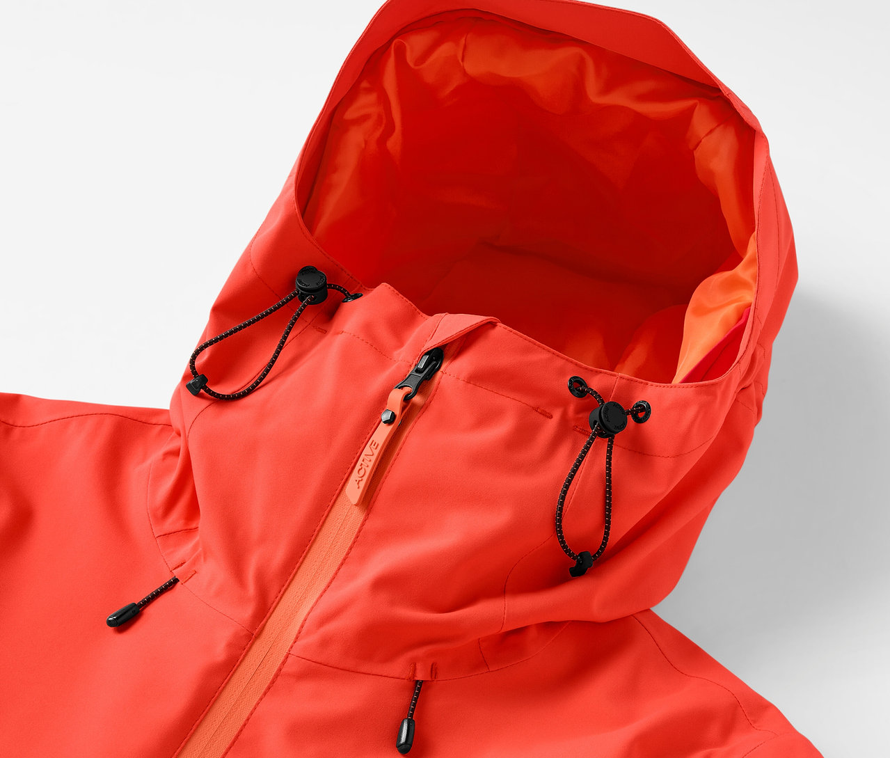 Zbliżenie na pomarańczową kurtkę z kapturem ze sznurkiem i zamkiem błyskawicznym.