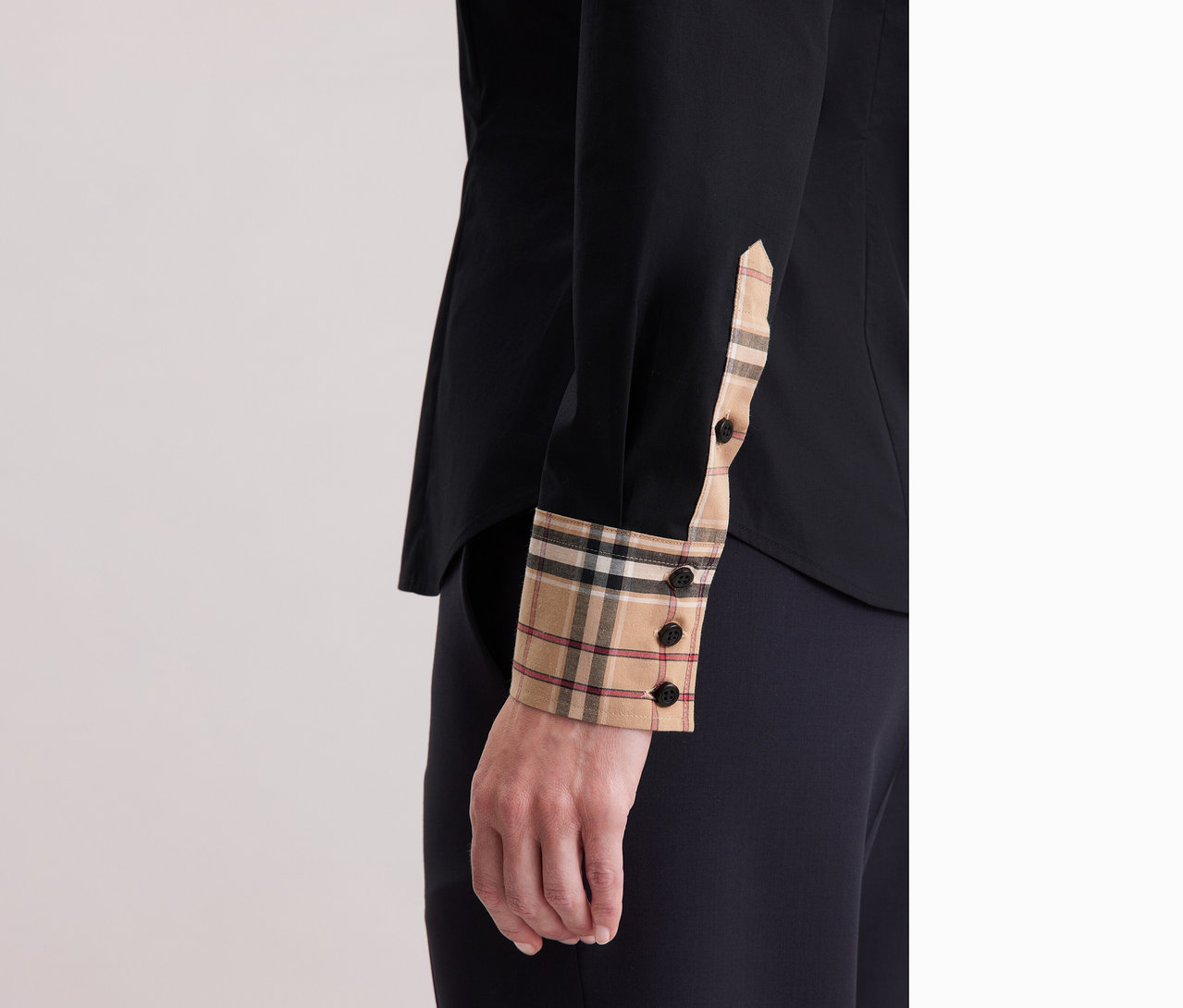 Na zdjęciu zbliżenie kobiety ubranej w popelinową bluzkę Seidensticker z detalami w kratę.