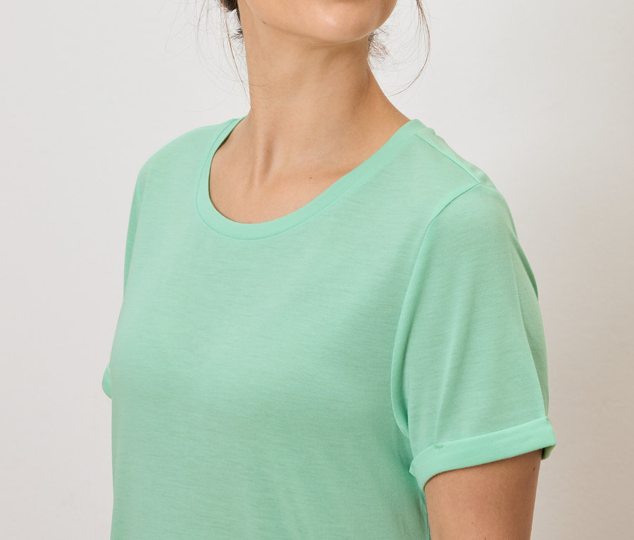 Kobieta ma na sobie jasnozieloną koszulkę.