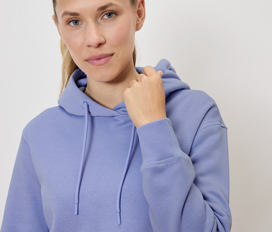 Portret blondynki w liliowej bluzie z kapturem, trzymającej kaptur.