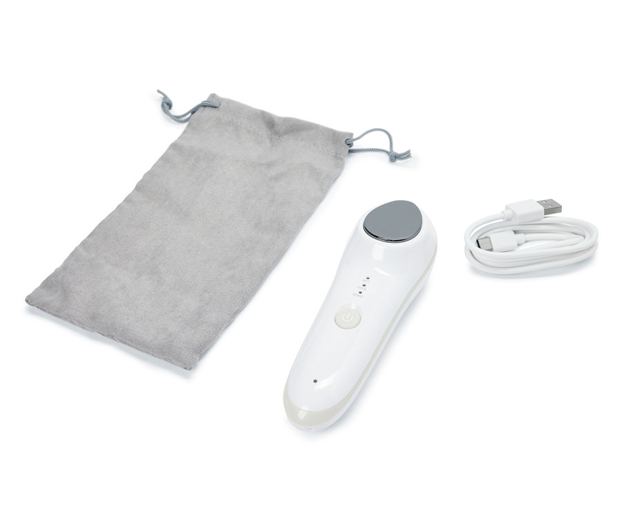 Na białym tle leży masażer wibracyjny do twarzy 4 w 1, szary woreczek i kabel USB.