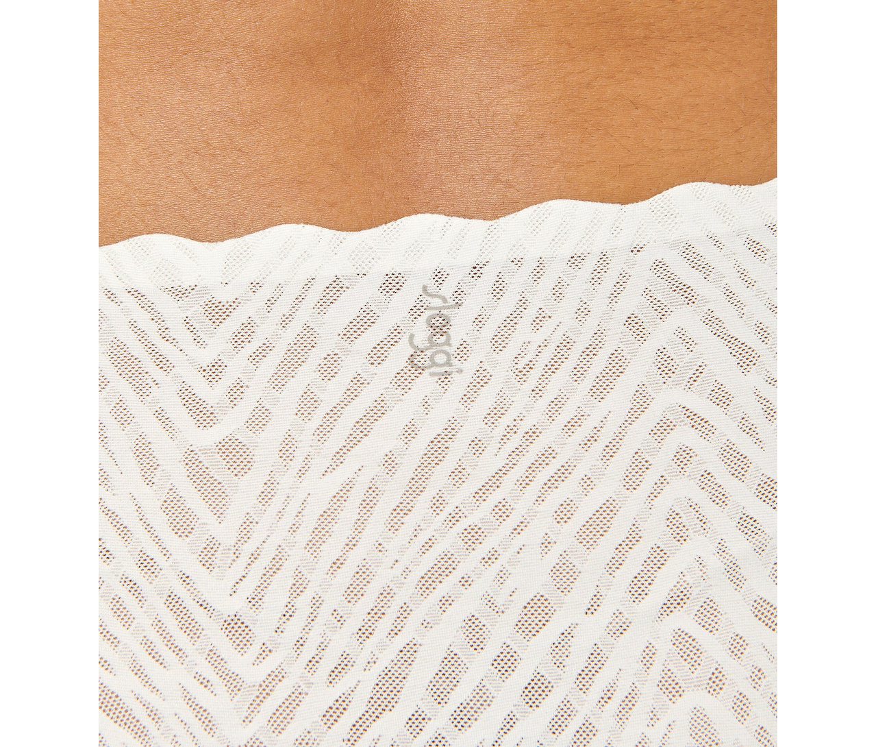 Zbliżenie na osobę w białych, wysokich figach sloggi ZERO Feel Bliss w kolorze silk white z ażurowym wzorem w zygzaki.