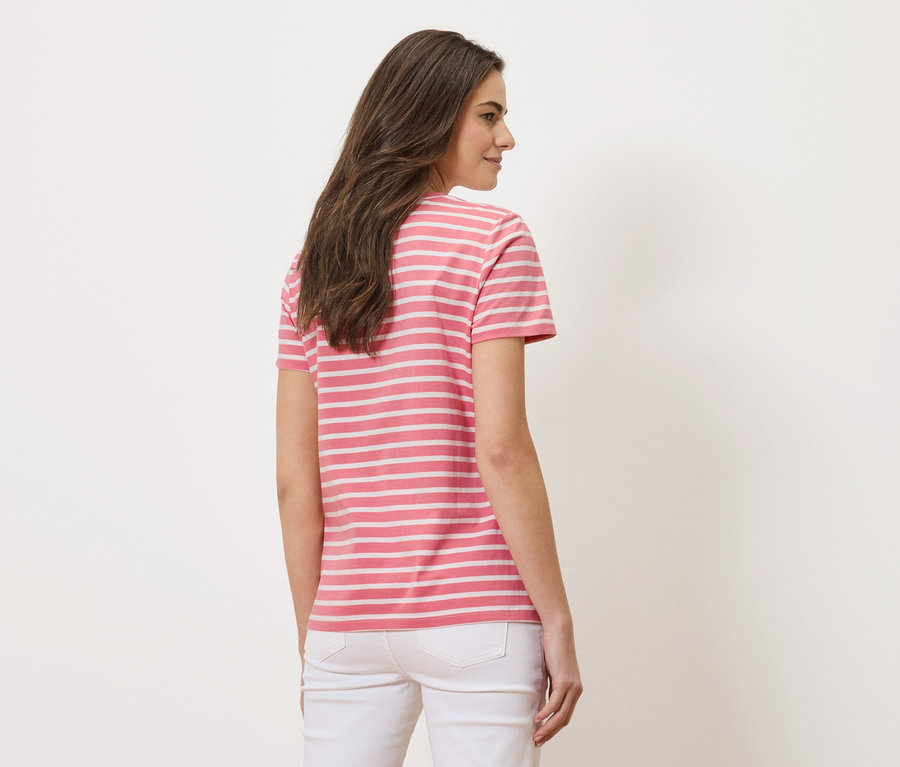 Kobieta widziana od tyłu, ubrana w różowo-białą koszulkę w paski i białe dżinsy.