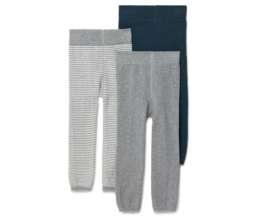 Trzy pary rajstop dziecięcych w kolorze szaro-białe paski, szarym i granatowym leżą obok siebie.