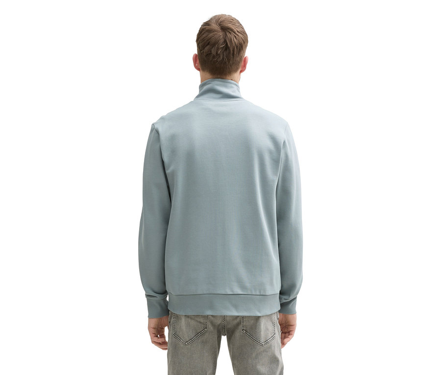 Tył mężczyzny w bluzie dresowej ze stójką Tom Tailor, Grey Mint i szarych dżinsach.