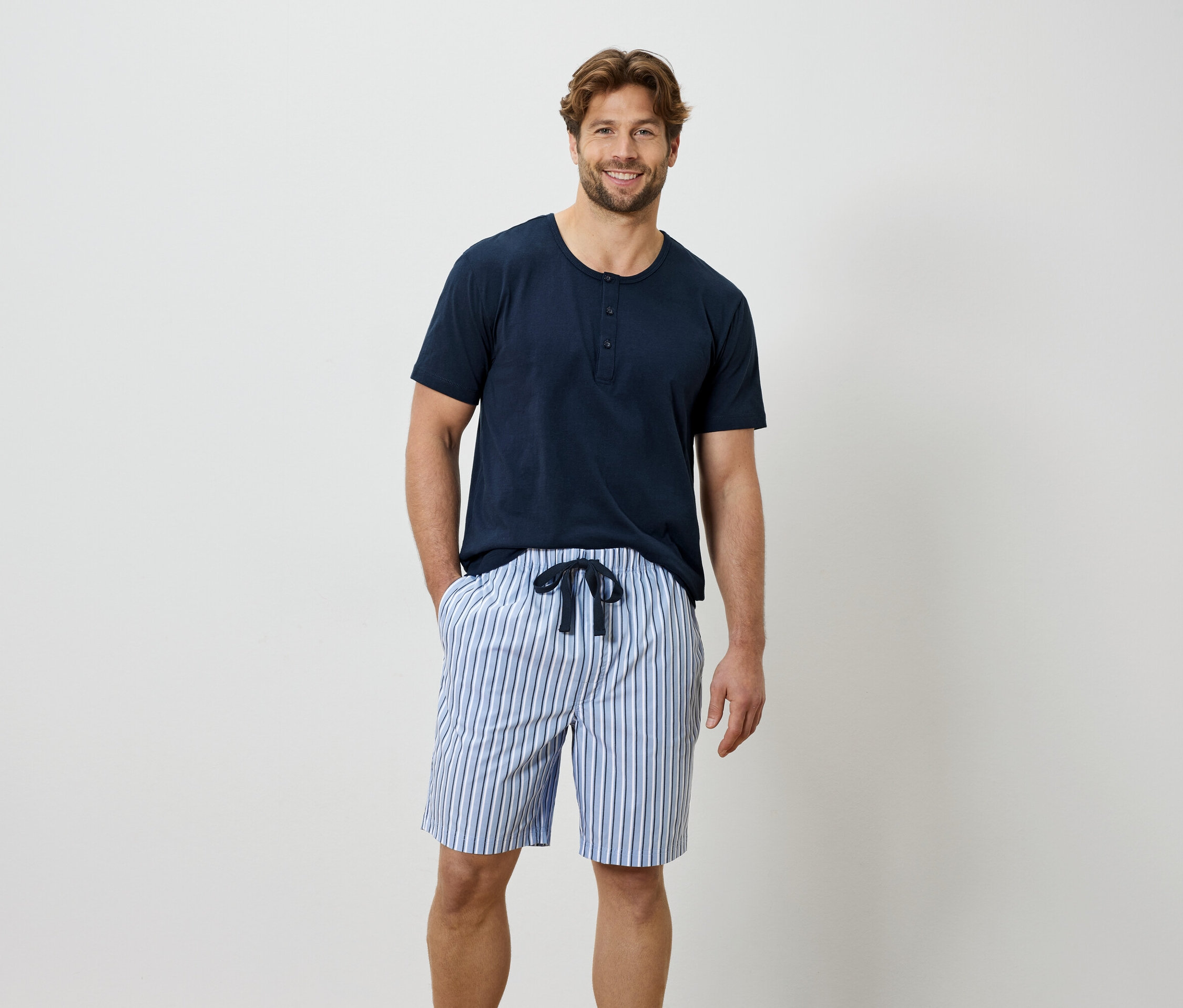 Mężczyzna w niebieskiej koszulce i szortach w paski.