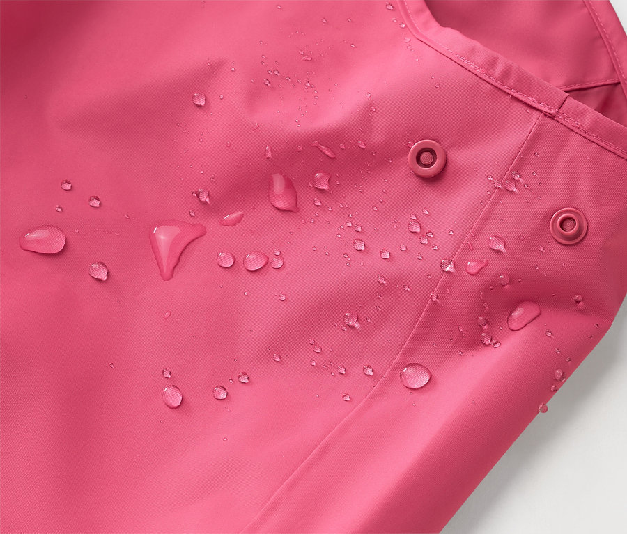 Zbliżenie różowej kurtki z kroplami wody i dwoma zatrzaskami.