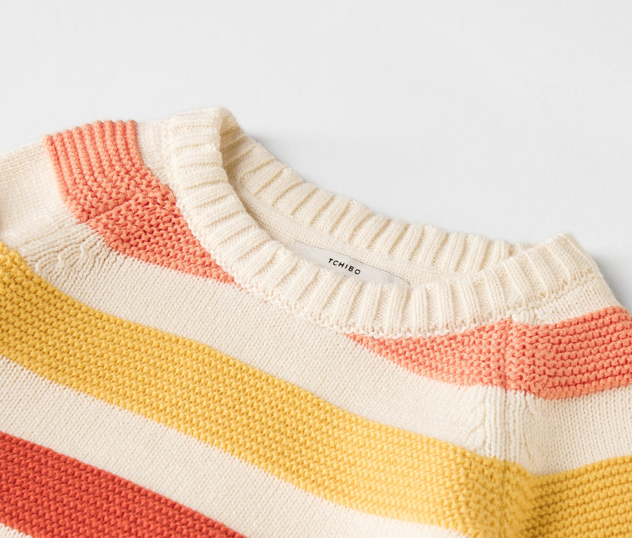 Zbliżenie na pasiasty sweter w kolorze żółtym, różowym i beżowym.