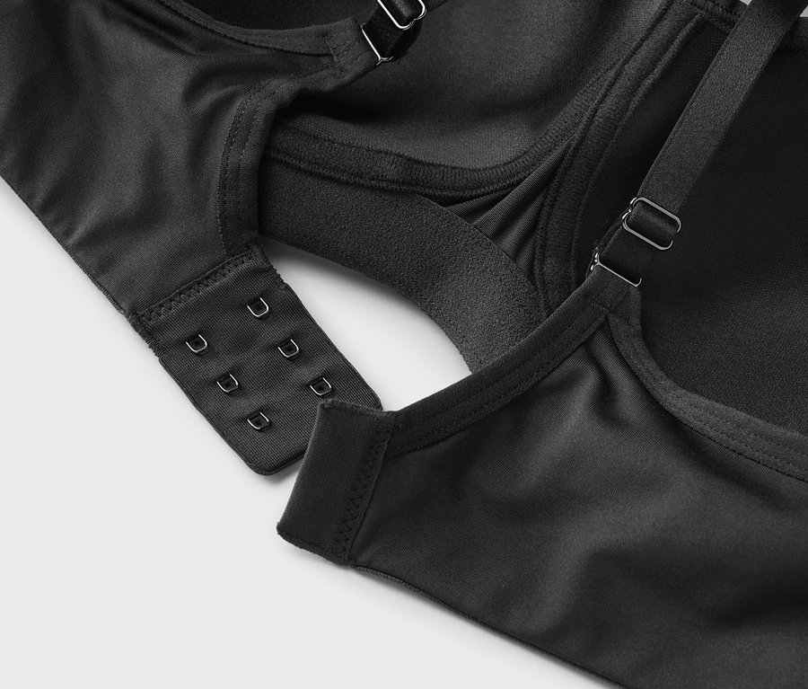 Zdjęcie z bliska czarnego biustonosza z zapięciem na haftki i regulowanymi ramiączkami.