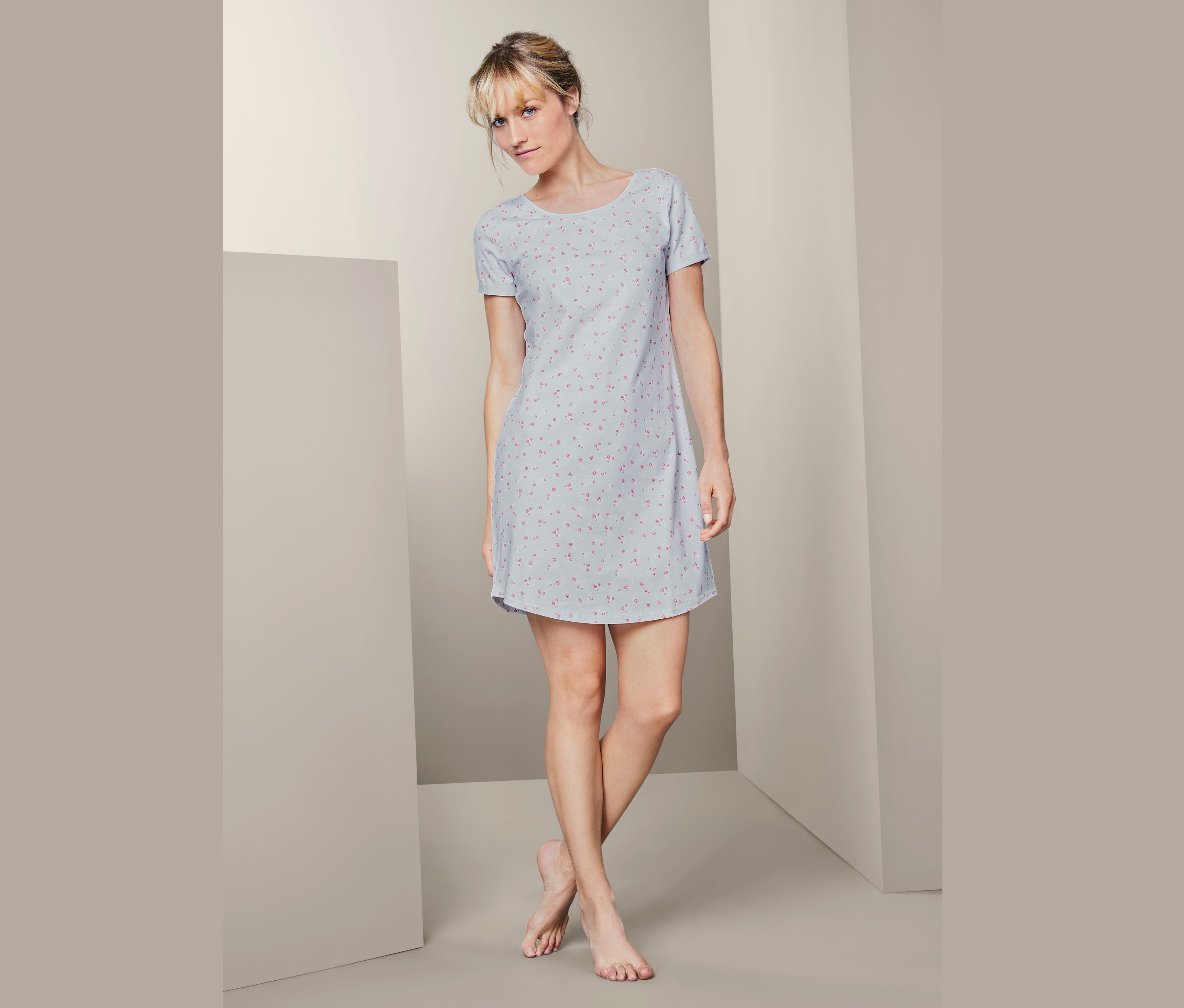 Kobieta stoi i ma na sobie koszulę nocną z krótkim rękawem.