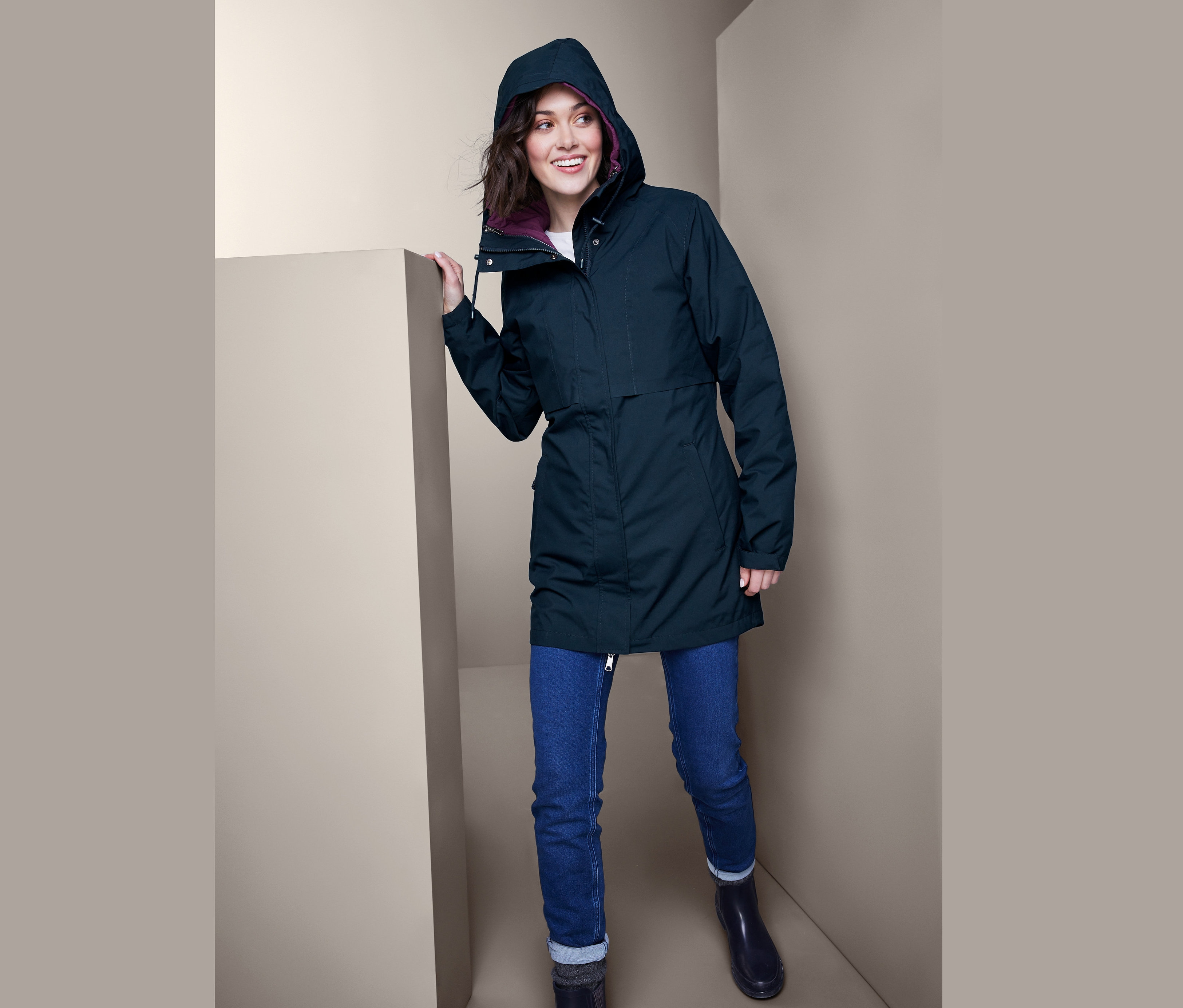 Uśmiechnięta kobieta pozuje w granatowym damskim płaszczu funkcyjnym 3 w 1, dżinsach i kaloszach.