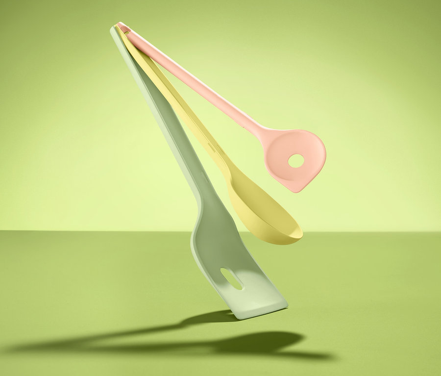 Trzy akcesoria kuchenne w odcieniach zieleni, żółci i różu unoszą się na zielonym tle. Akcesoria kuchenne, 3 sztuki.