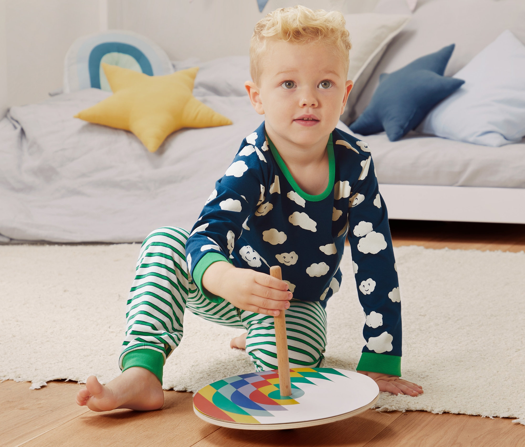 Chłopiec bawi się kolorową zabawką na podłodze, ubrany w piżamy z bawełny ekologicznej, 2 sztuki.