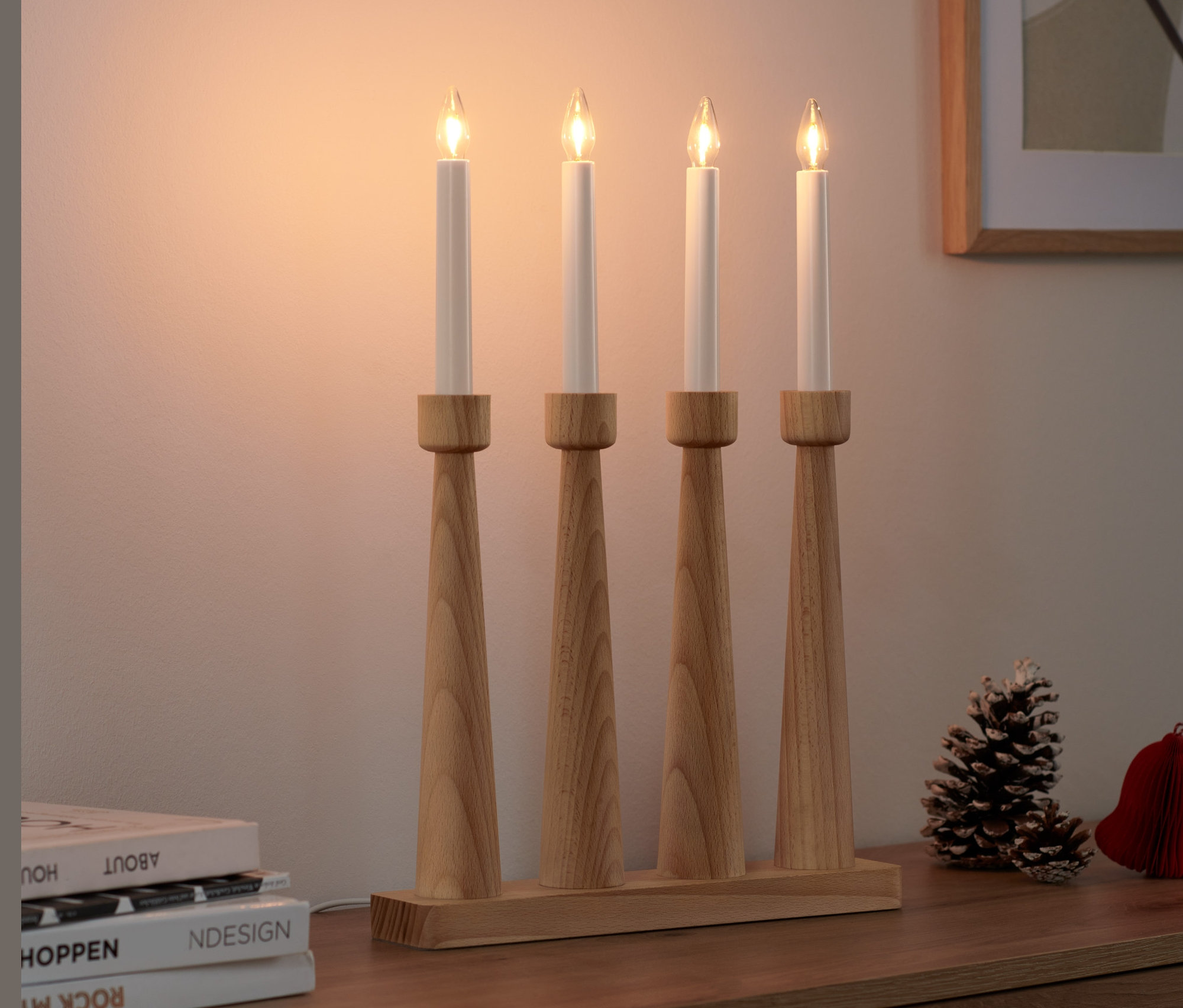 Cztery świece LED w drewnianym świeczniku stoją na szafce.