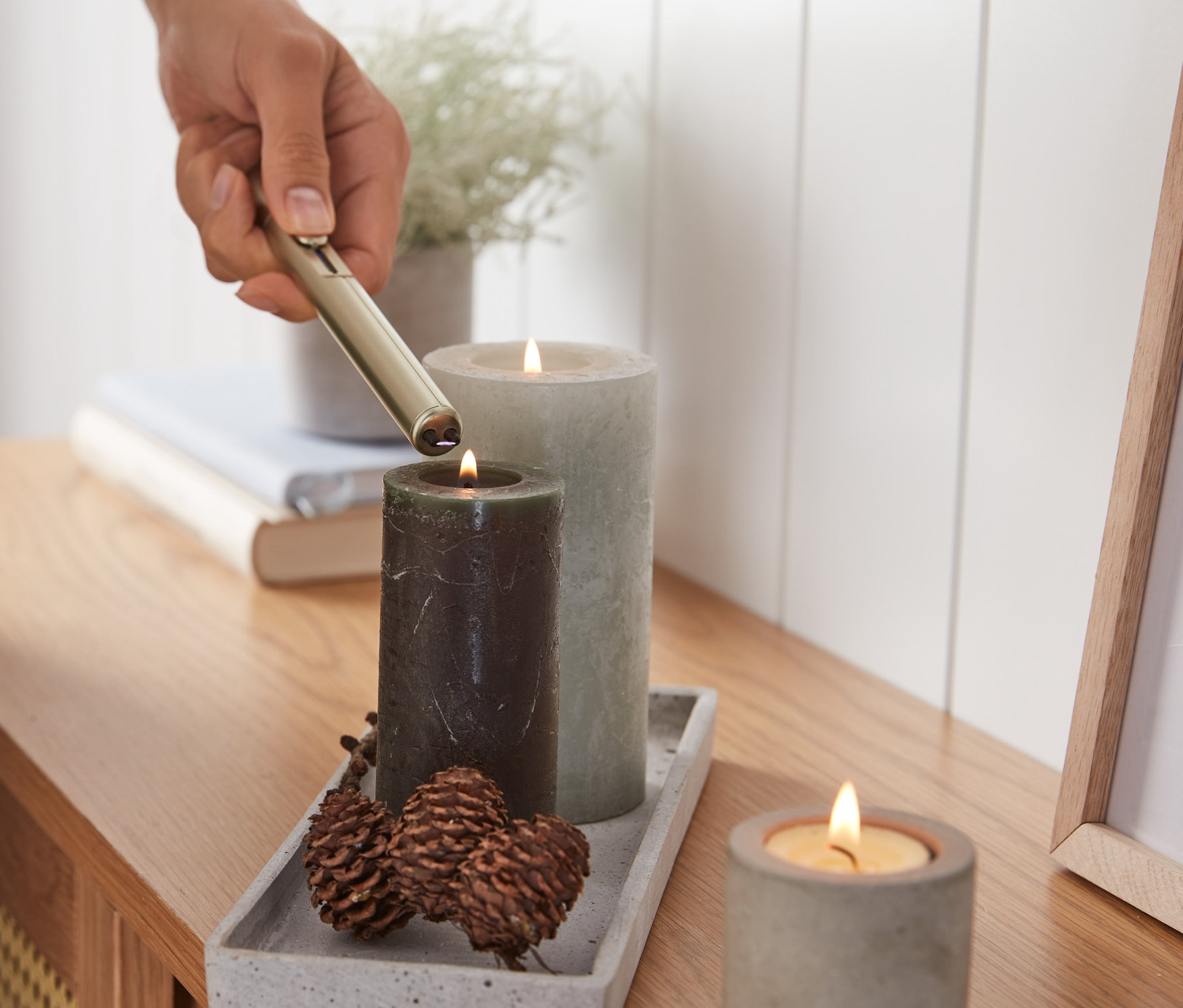 Osoba zapala świecę elektryczną zapalniczką na łuk elektryczny.