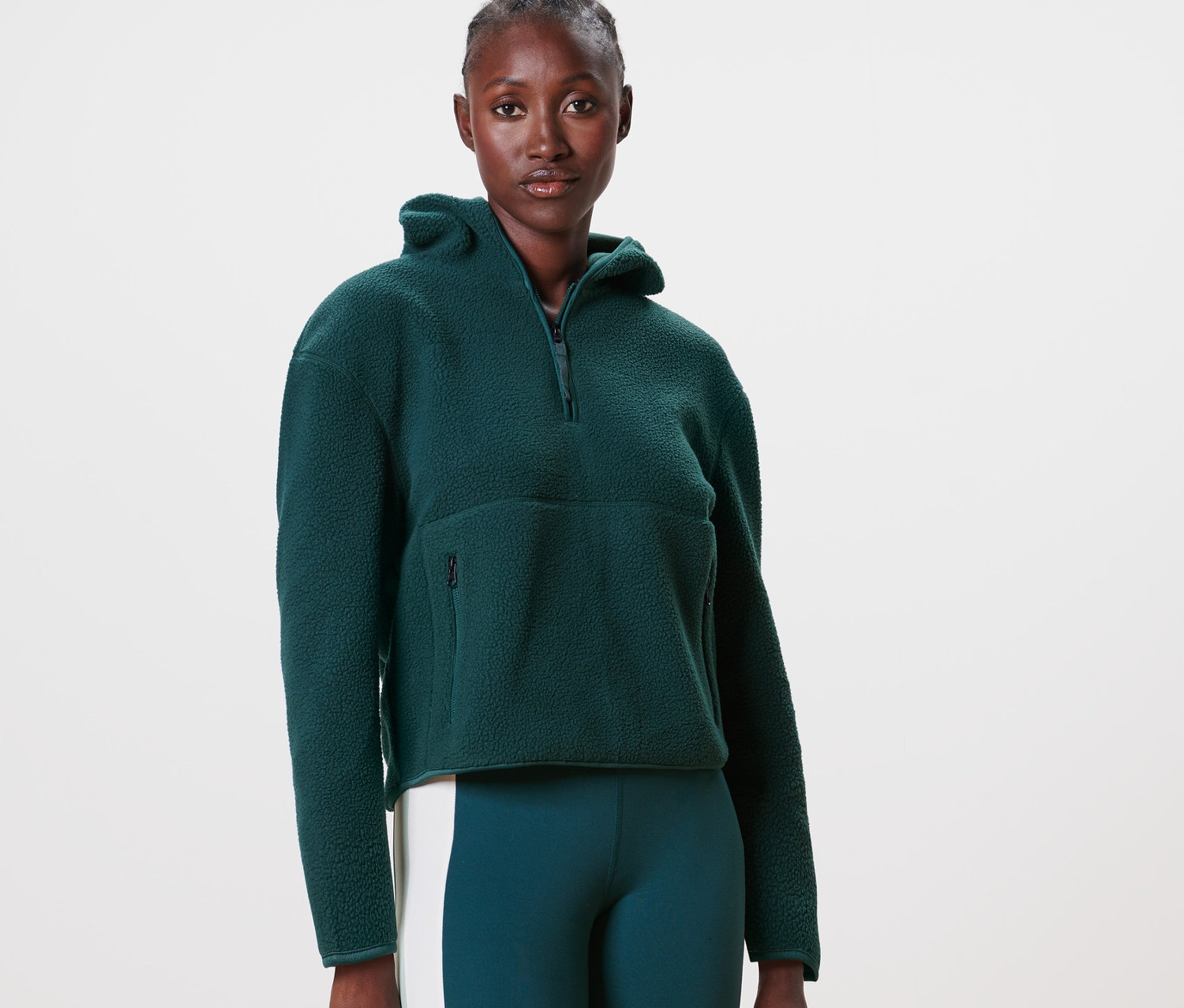 Kobieta ma na sobie bluzę z kapturem z pluszu, ciemnozieloną.