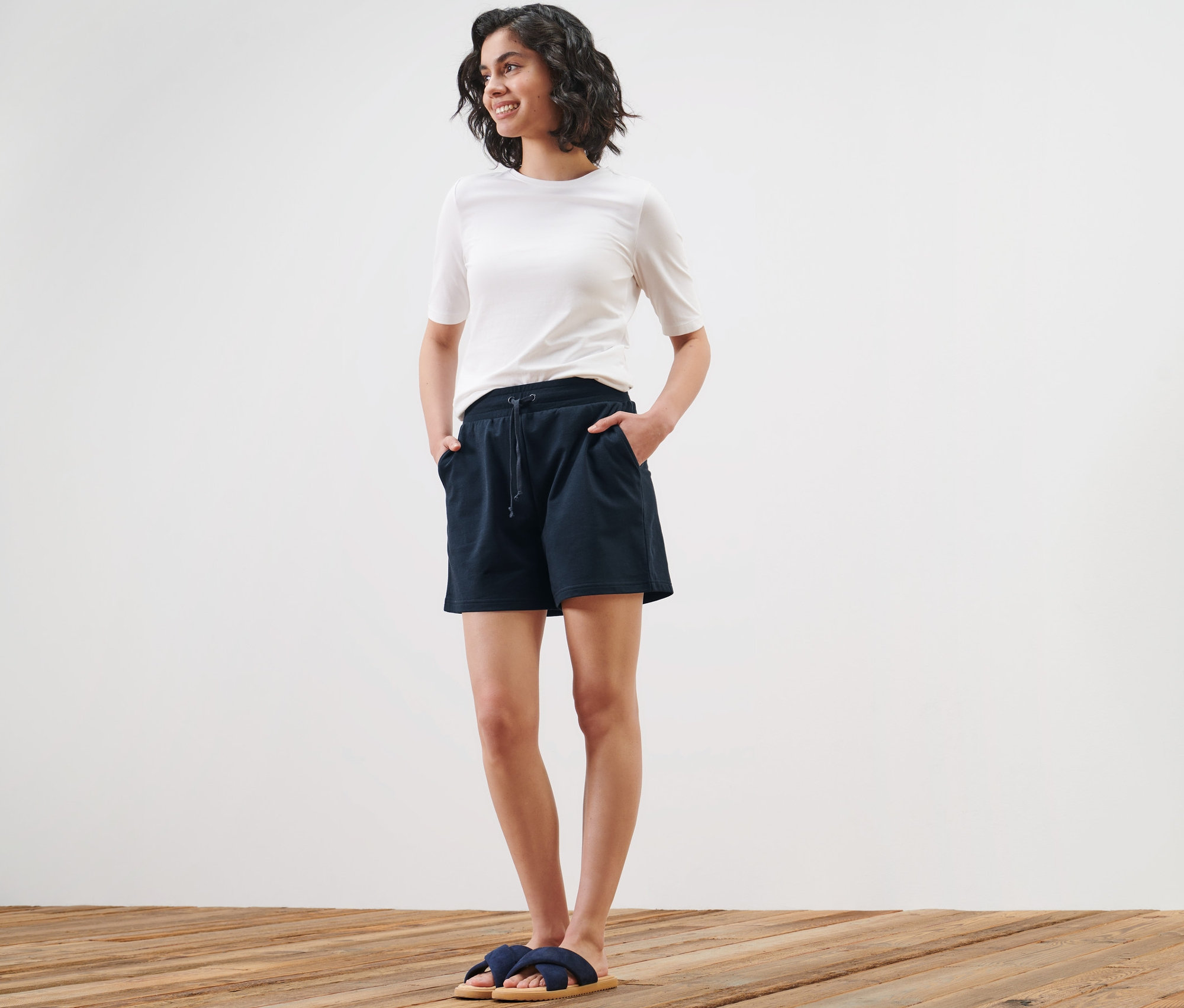 Kobieta pozuje w szortach dresowych i t-shircie.