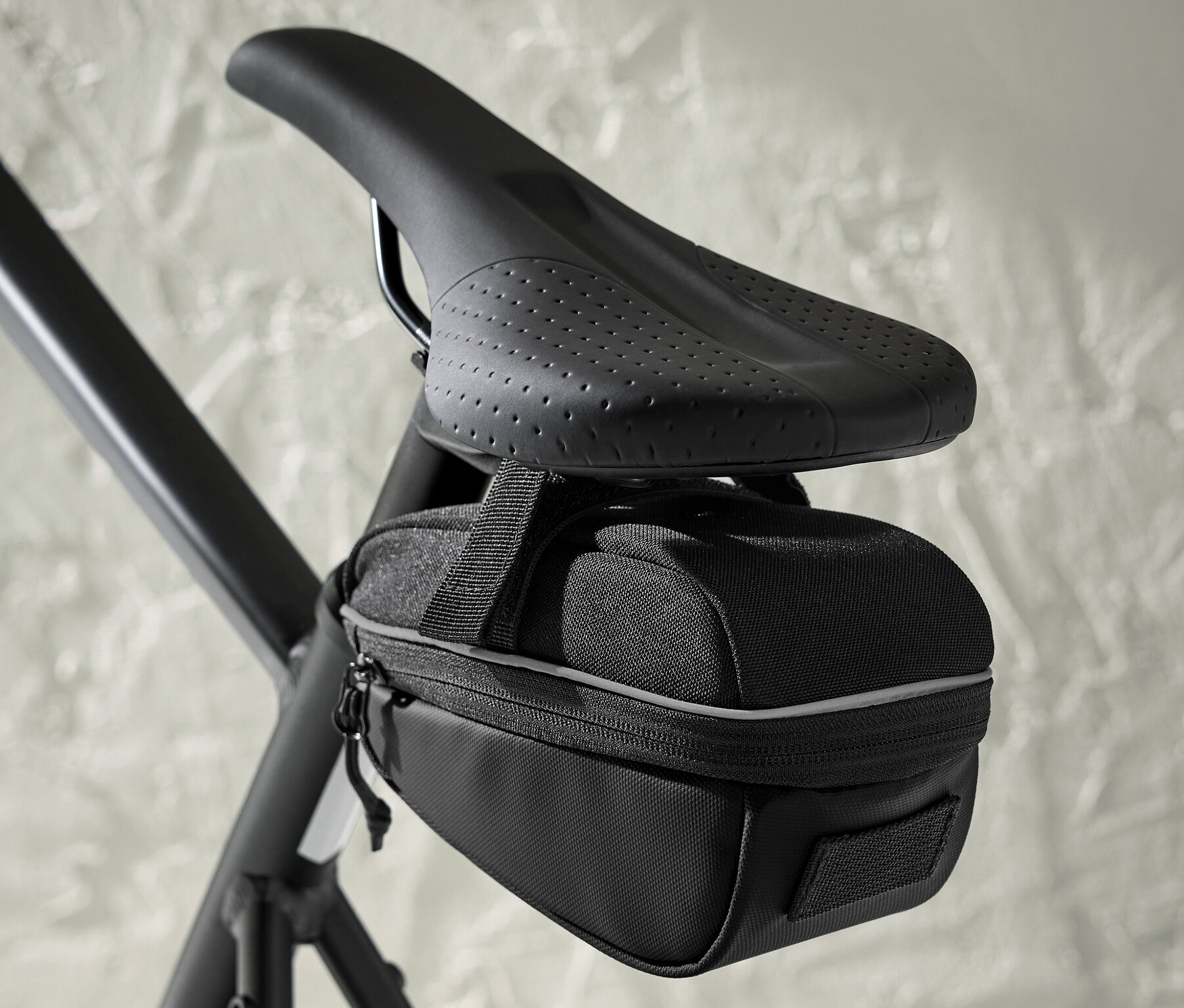 Czarna torba pod siodełkiem rowerowym przymocowana do siodełka roweru.