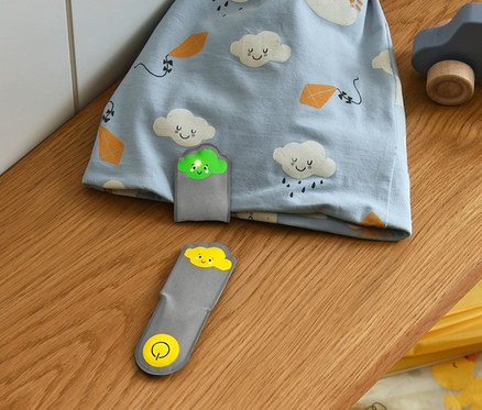 Niebieska czapka we wzór w chmury i światełka LED na magnes »Chmury«, 2 sztuki leżą na półce.