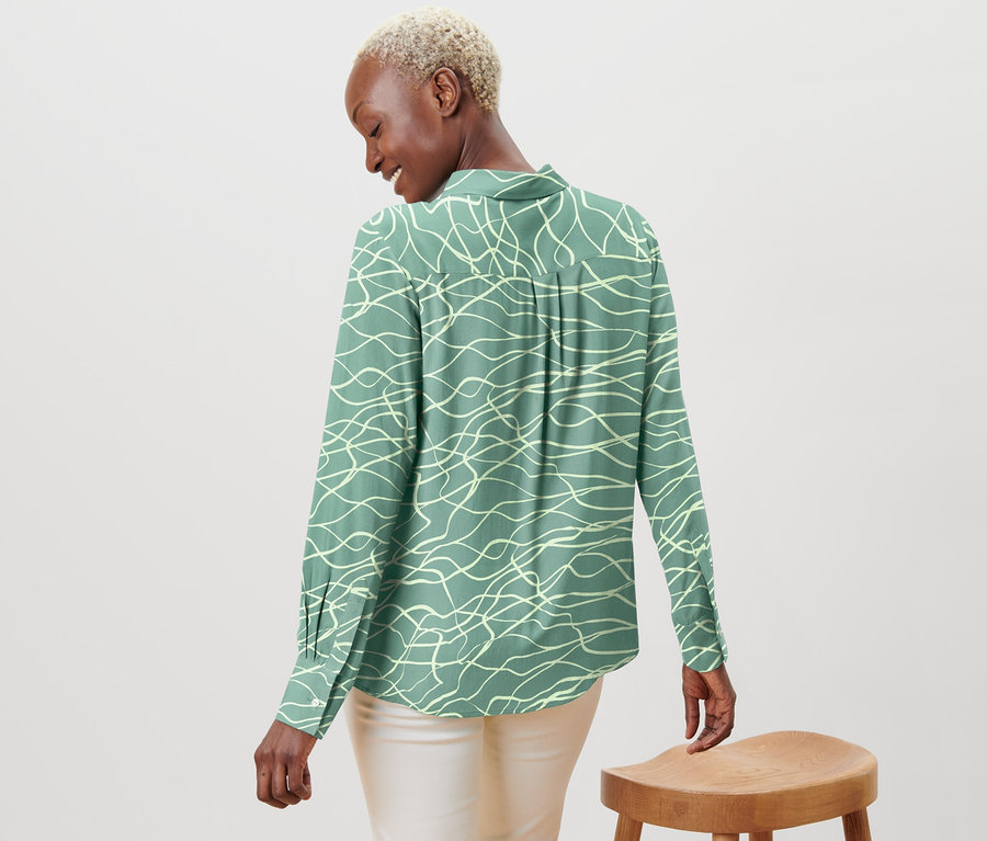 Kobieta patrzy przez ramię, ma na sobie bluzkę z nadrukiem.