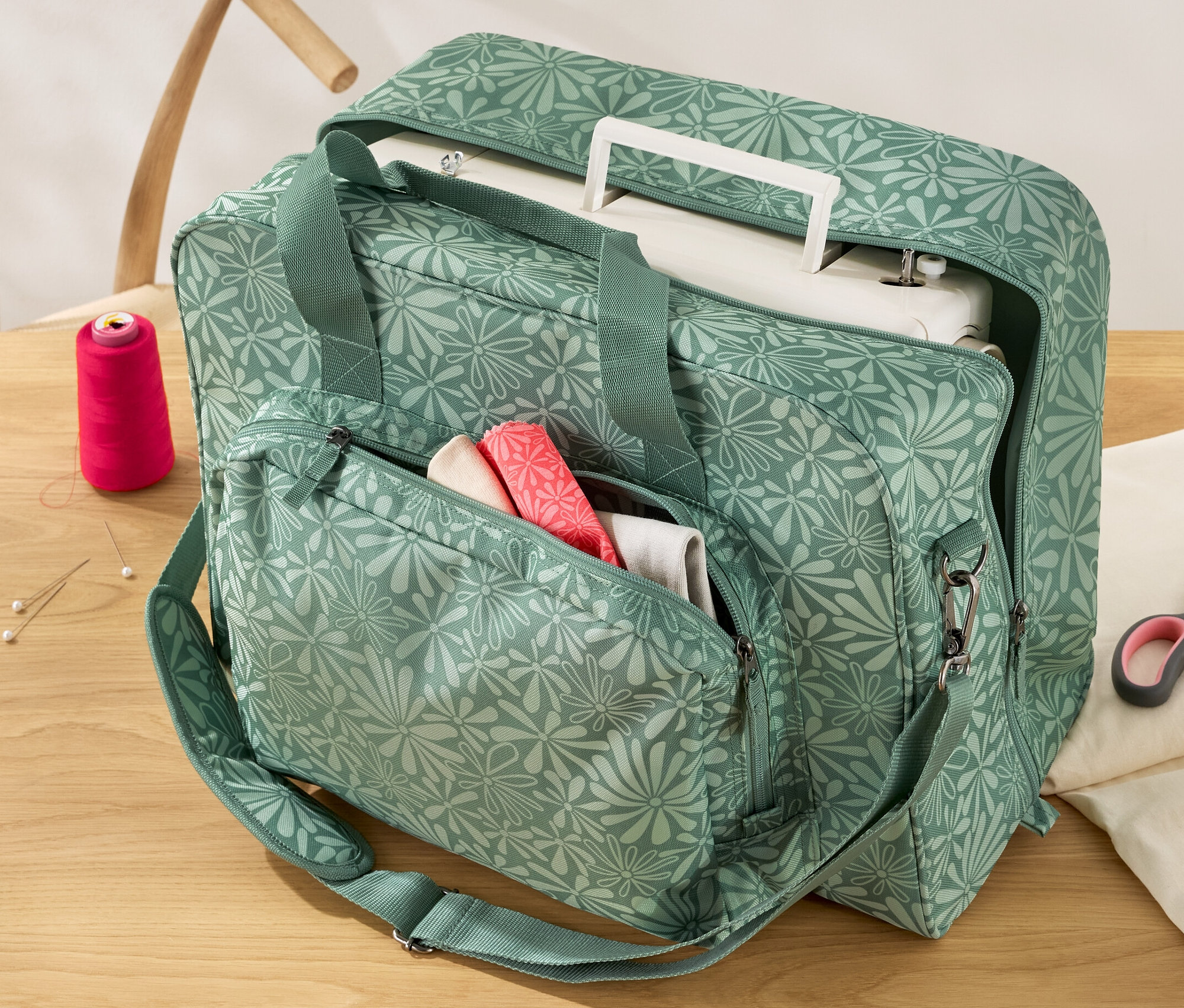 Zielona torba na maszynę do szycia w kwiaty na drewnianym stole.