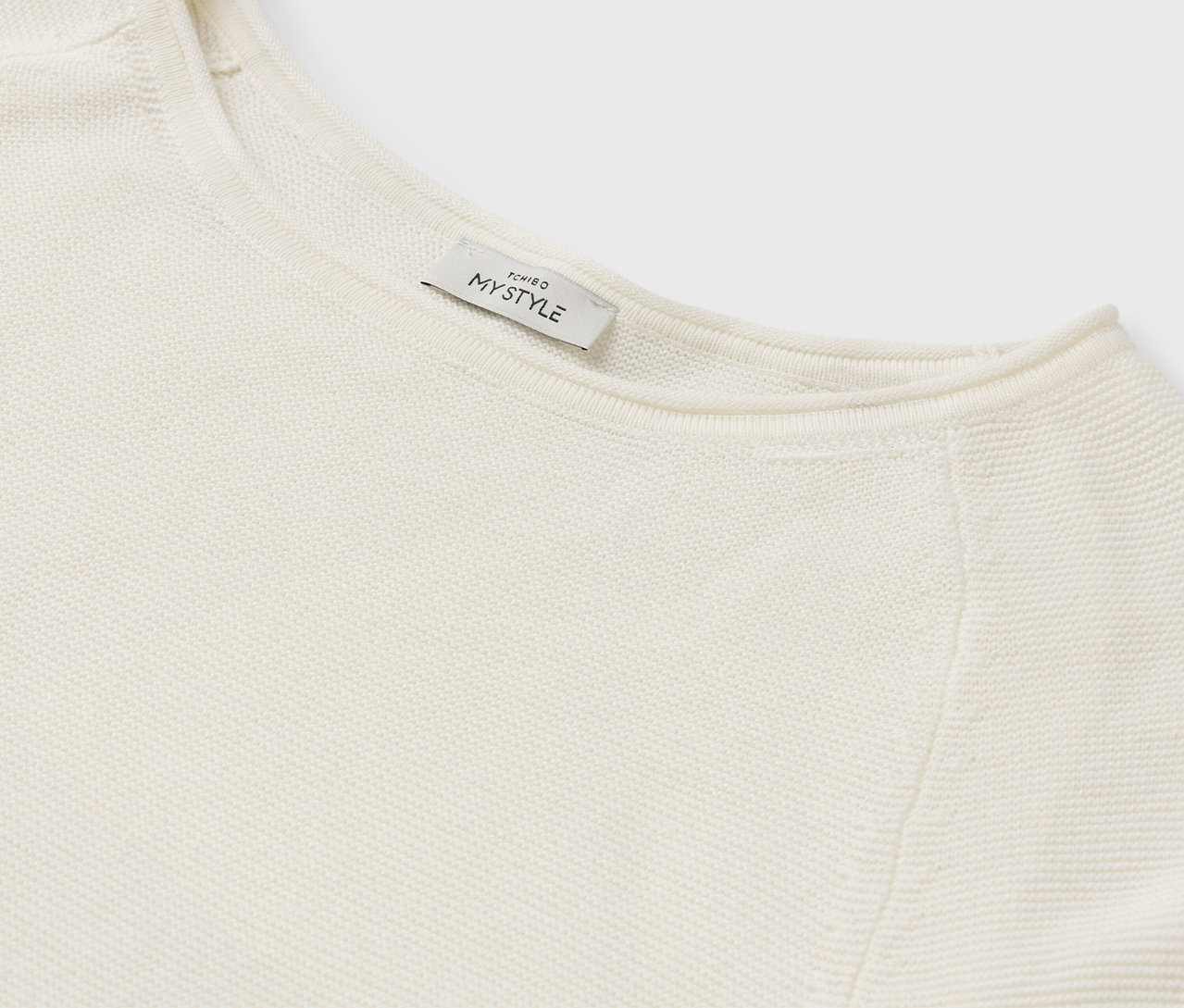 Szczegół kremowego swetra z metką MY STYLE.