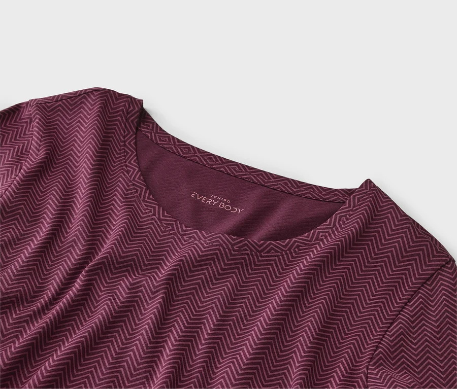 Zbliżenie na bordowy T-shirt w zygzaki z napisem "EVERY BODY" na dekolcie.
