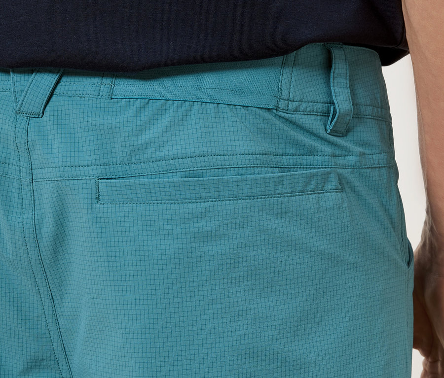 Zbliżenie na tył turkusowych spodni z kieszeniami.