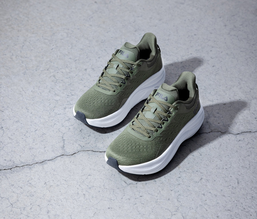 Dwa oliwkowozielone buty do biegania Fila stoją na szarym tle.