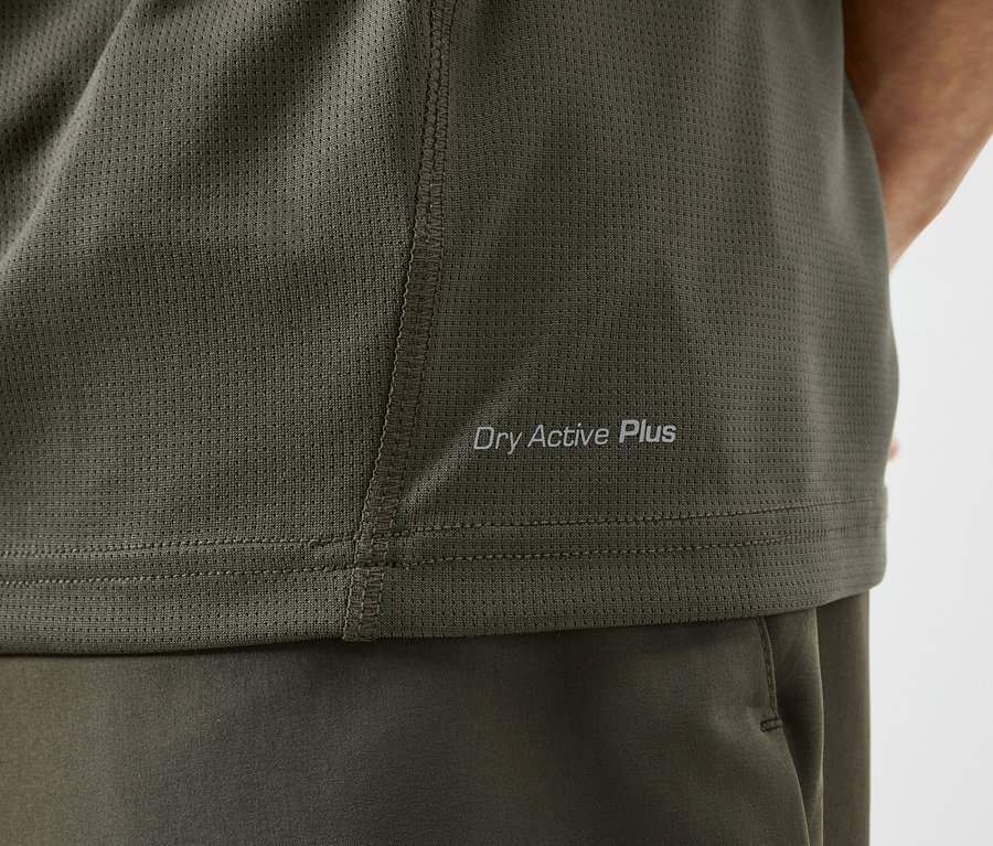 Zbliżenie oliwkowej koszulki sportowej z napisem "Dry Active Plus".