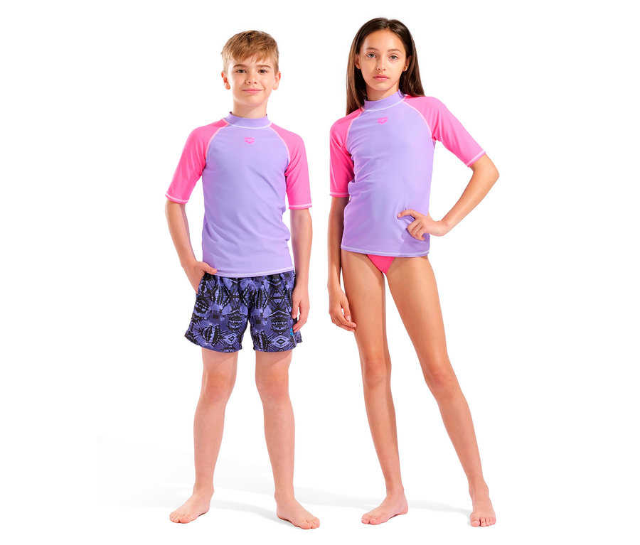Chłopiec w liliowo-różowej koszulce kąpielowej z krótkim rękawem i wzorzystych szortach kąpielowych stoi obok dziewczynki w liliowo-różowej koszulce kąpielowej z krótkim rękawem i różowych majtkach kąpielowych.