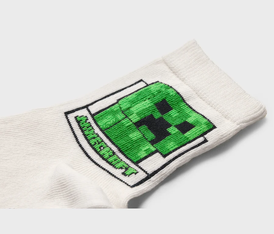 Zbliżenie białej skarpety z zielonym motywem Creepera z Minecrafta.