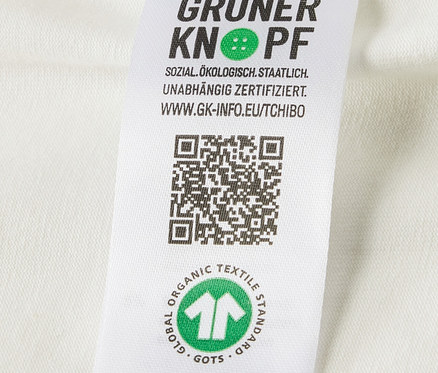 Zbliżenie na etykietę z logo i certyfikatem bawełny organicznej na body niemowlęcym rosnącym z dzieckiem, 5 par.