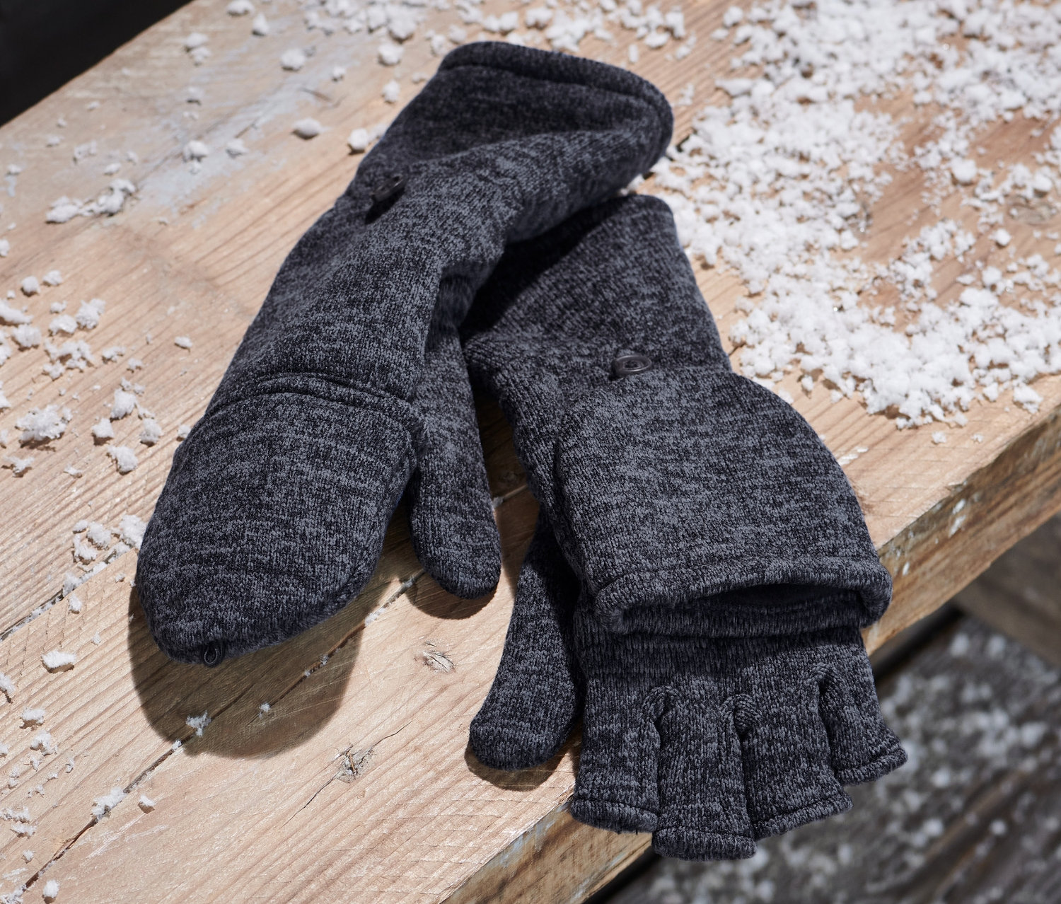 Niebieskie rękawice-łapawice z dzianiny polarowej leżą na drewnianej ławce obok płóciennego plecaka.