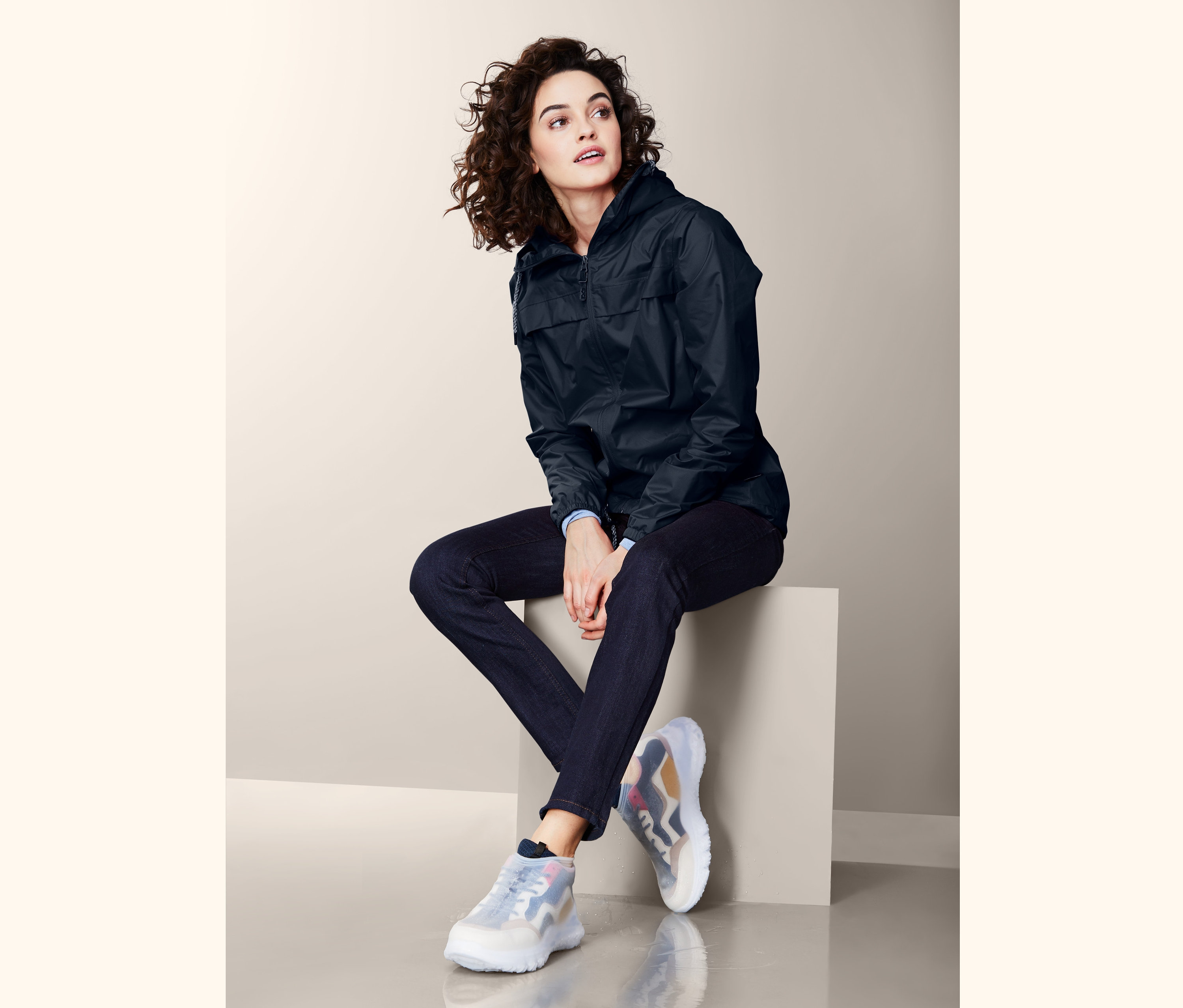 Kobieta siedzi na bloku, ma na sobie ochraniacze przeciwdeszczowe na buty.