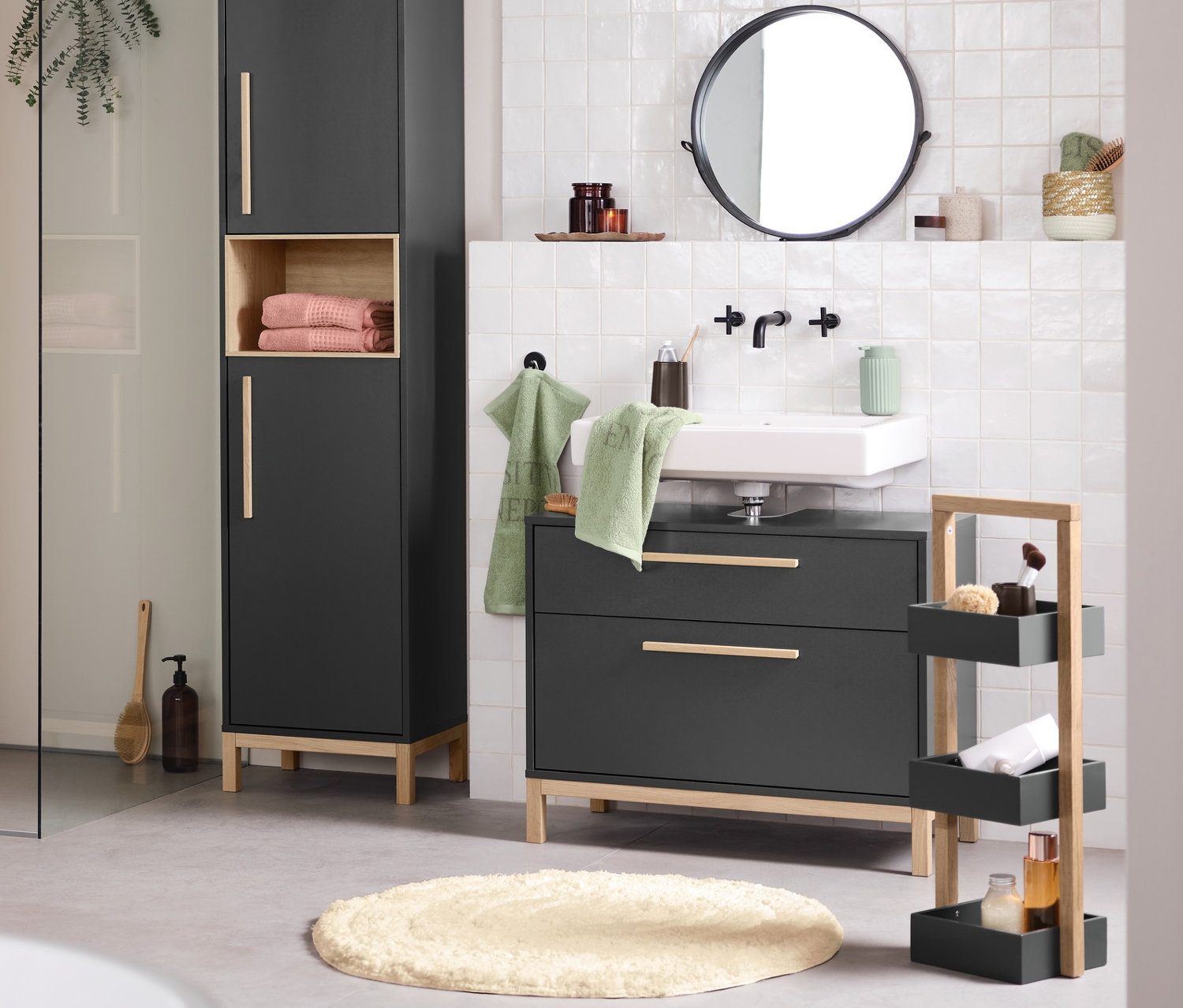 Wnętrze łazienki z umywalką, lustrem i antracytowymi szafkami łazienkowymi Eklund. Na pierwszym planie wanna.