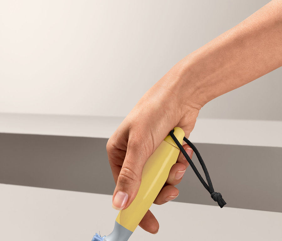 Ręka trzyma uniwersalną szczotkę do czyszczenia i czyści powierzchnię.