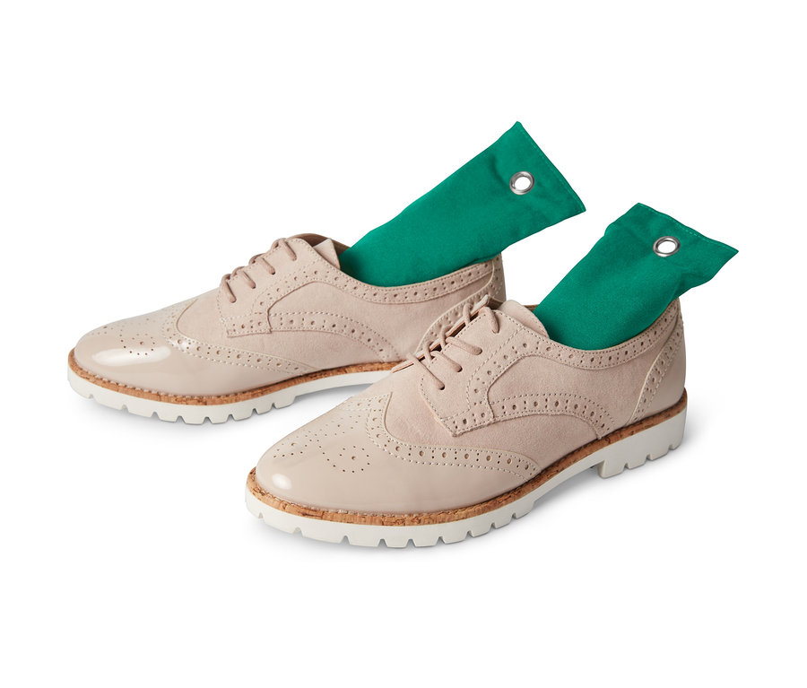 Dwa beżowe sznurowane buty z dwoma zielonymi poduszkami do usuwania zapachów z butów, 2 sztuki, włożonymi do środka.
