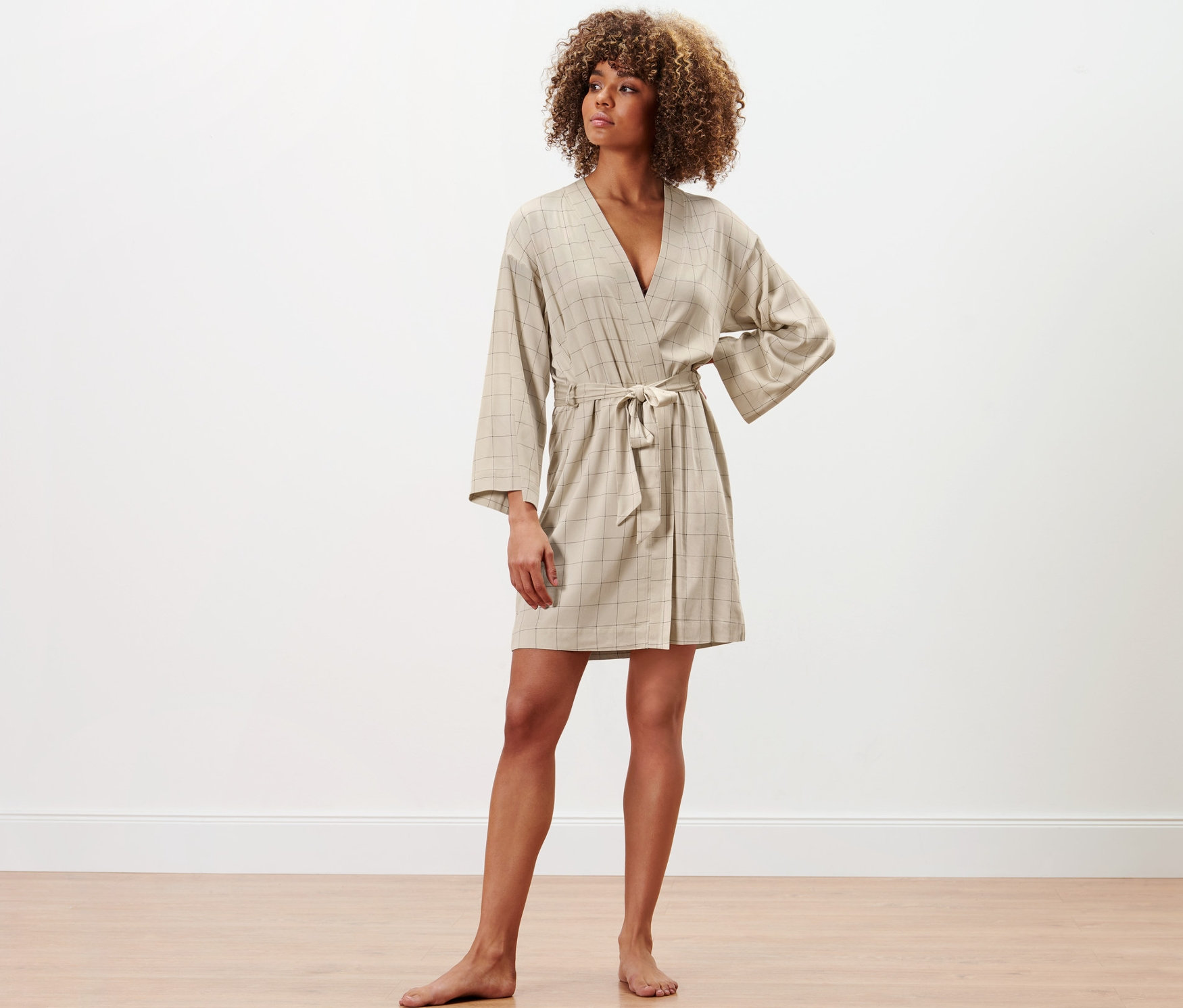 Kobieta stoi i pozuje w szlafroku.