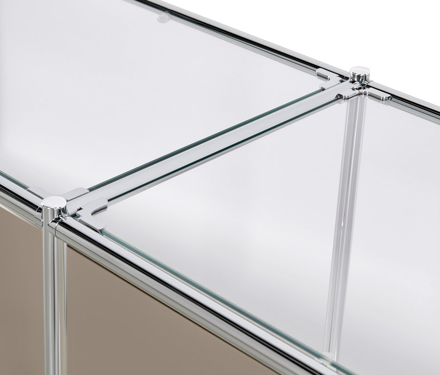 Zbliżenie na metalową szafkę typu sideboard „CN3” z klapami i szklaną półką, w kolorze szarobeżowym.