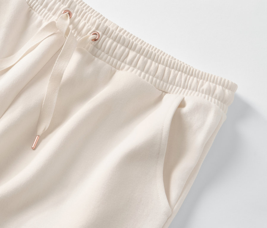 Szczegół kremowych spodni dresowych domowych z elastycznym pasem i sznurkiem.
