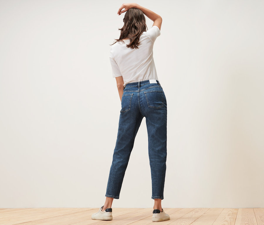 Kobieta pozuje w dżinsach typu Mom Jeans – fason „Nyla” i białym T-shircie.