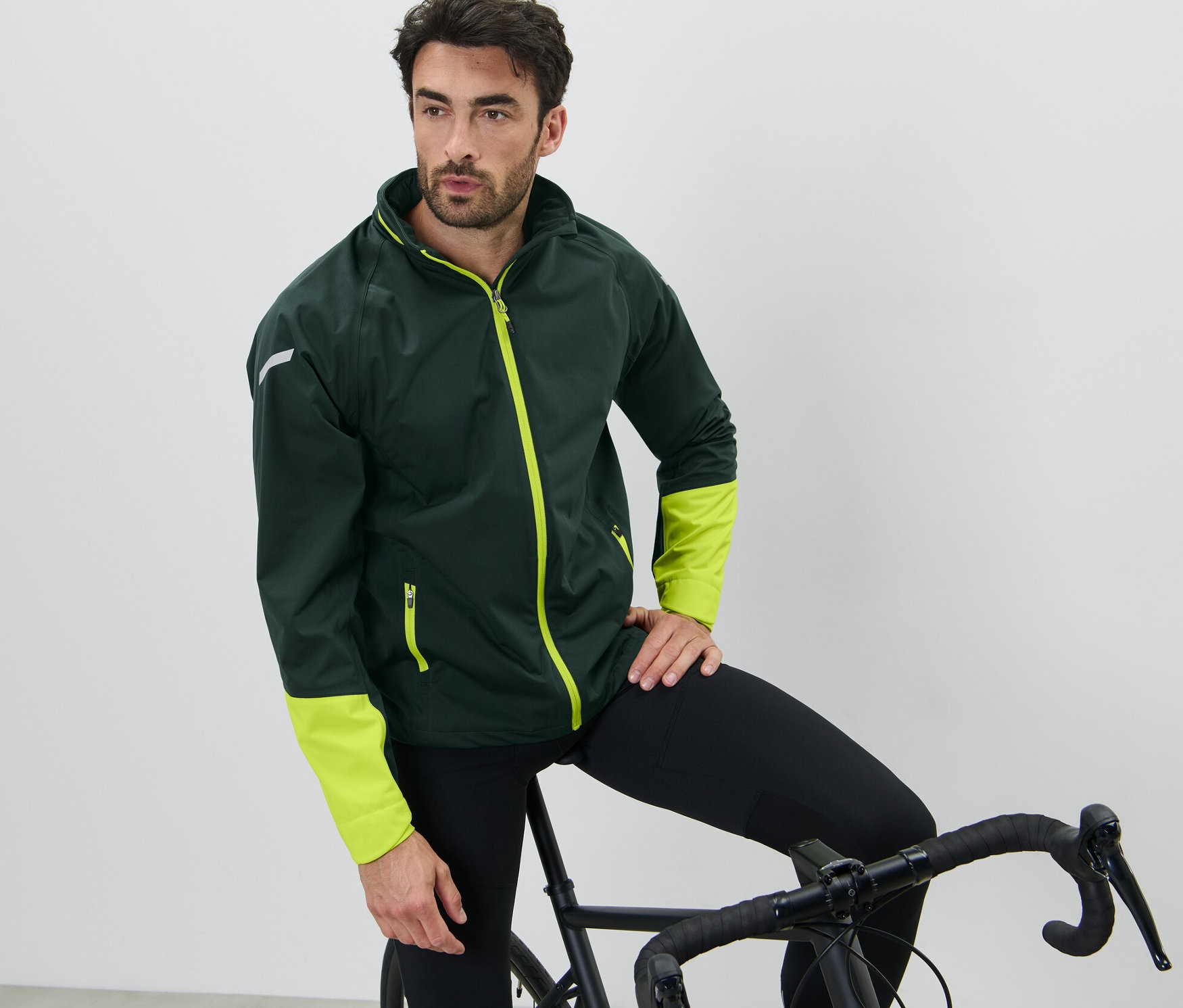 Mężczyzna opiera się o rower, ma na sobie kurtkę przeciwdeszczową na rower.