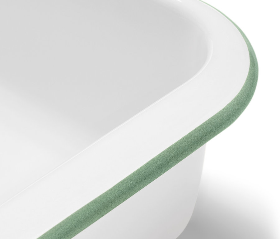 Zbliżenie na białą emaliowaną formę do zapiekania z pokrywką i zielonym obramowaniem.