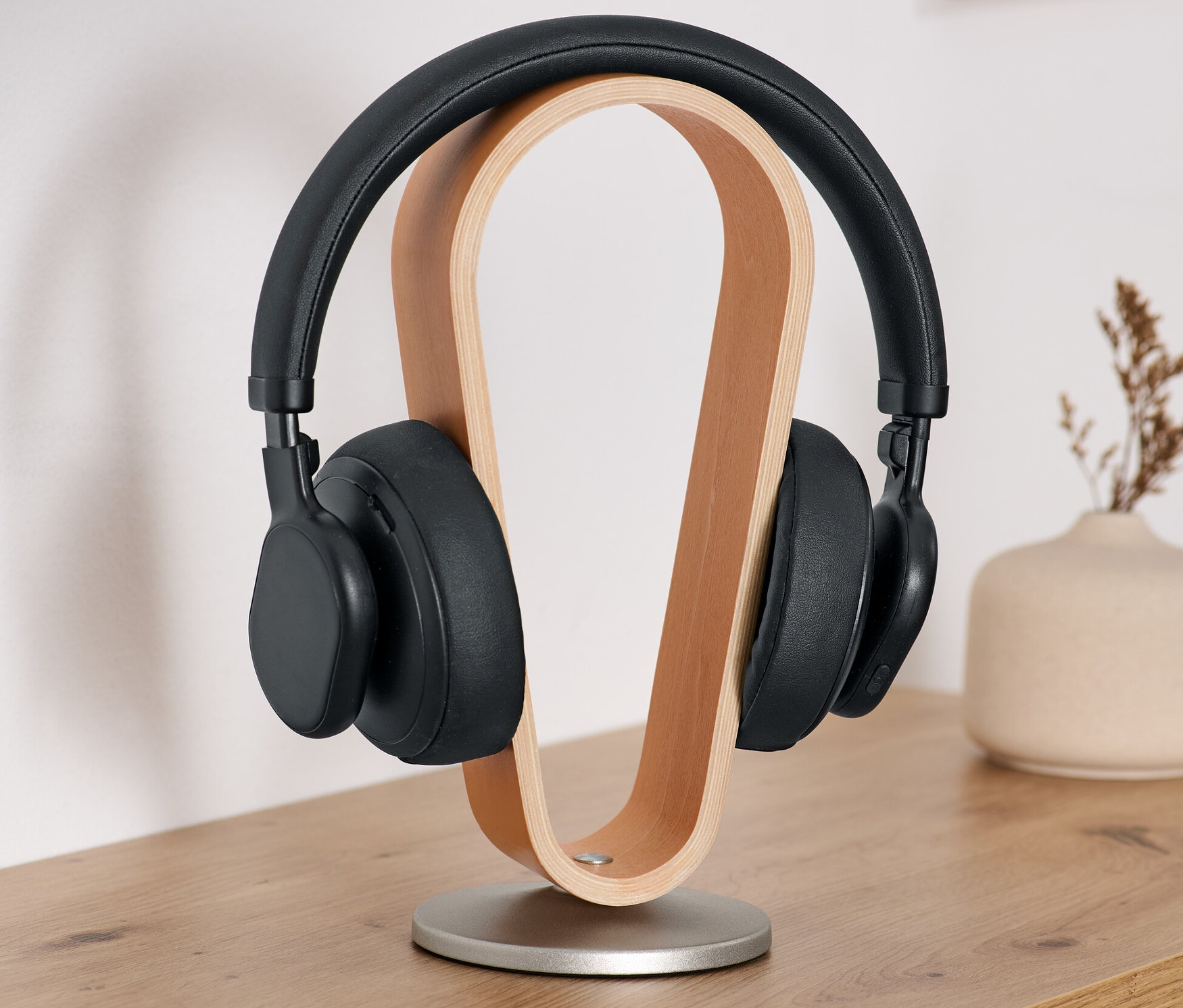 Czarne słuchawki na drewnianym stojaku na słuchawki.