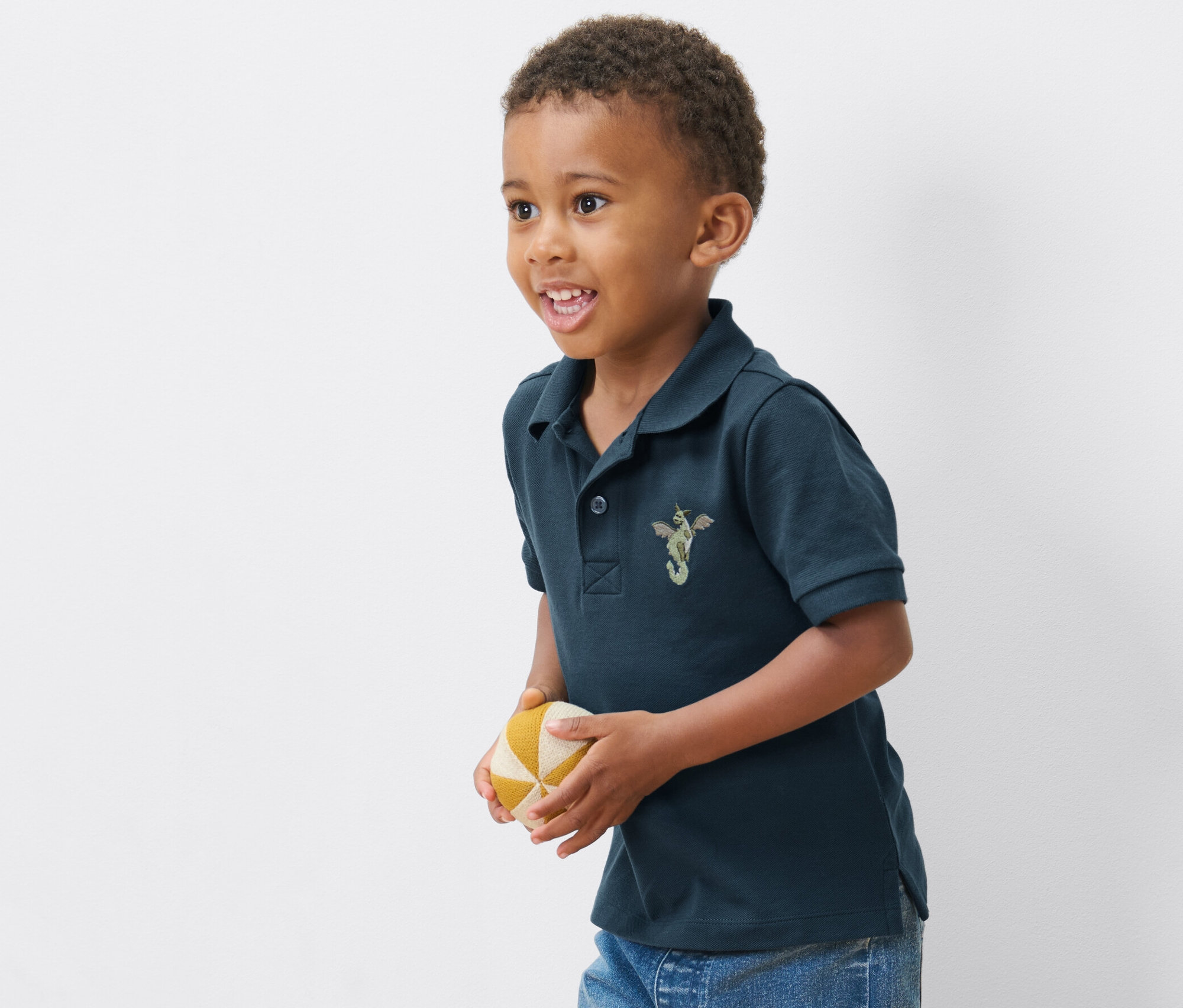 Chłopiec ma na sobie jedną z 2 koszulek polo z bawełny piqué i trzyma piłkę.