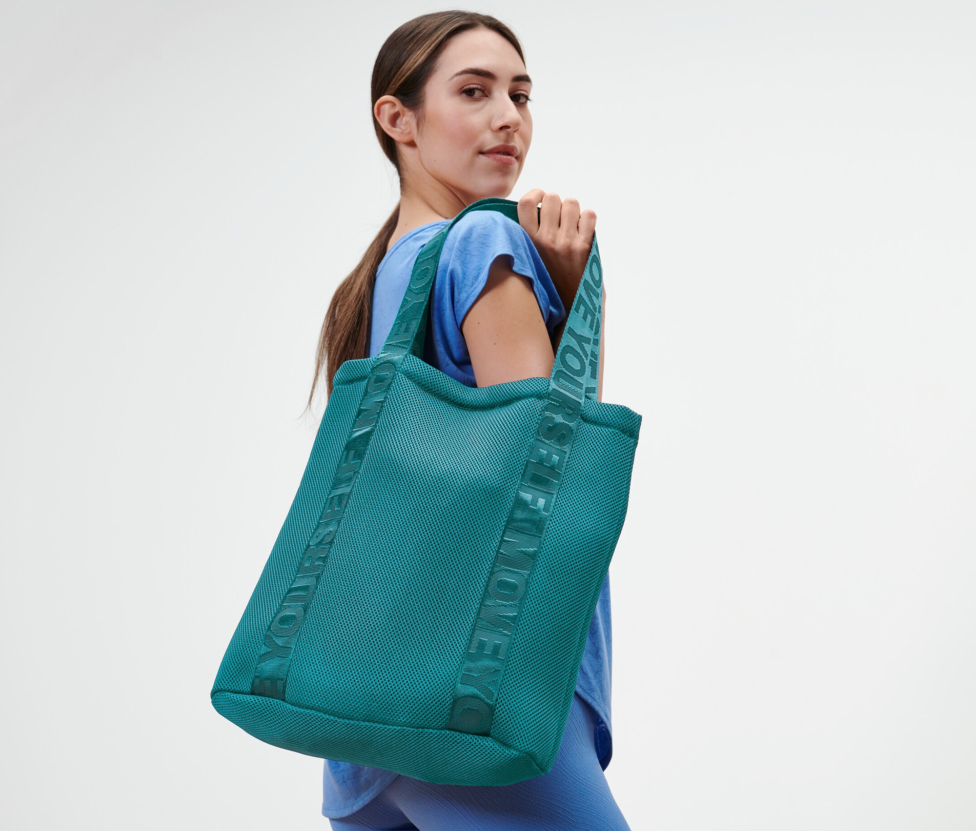 Kobieta pozuje z torbą sportową.