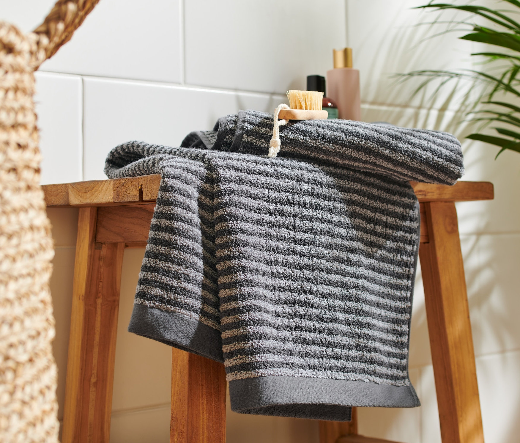 Na drewnianym stołku leżą dwa wysokiej jakości antracytowe ręczniki.