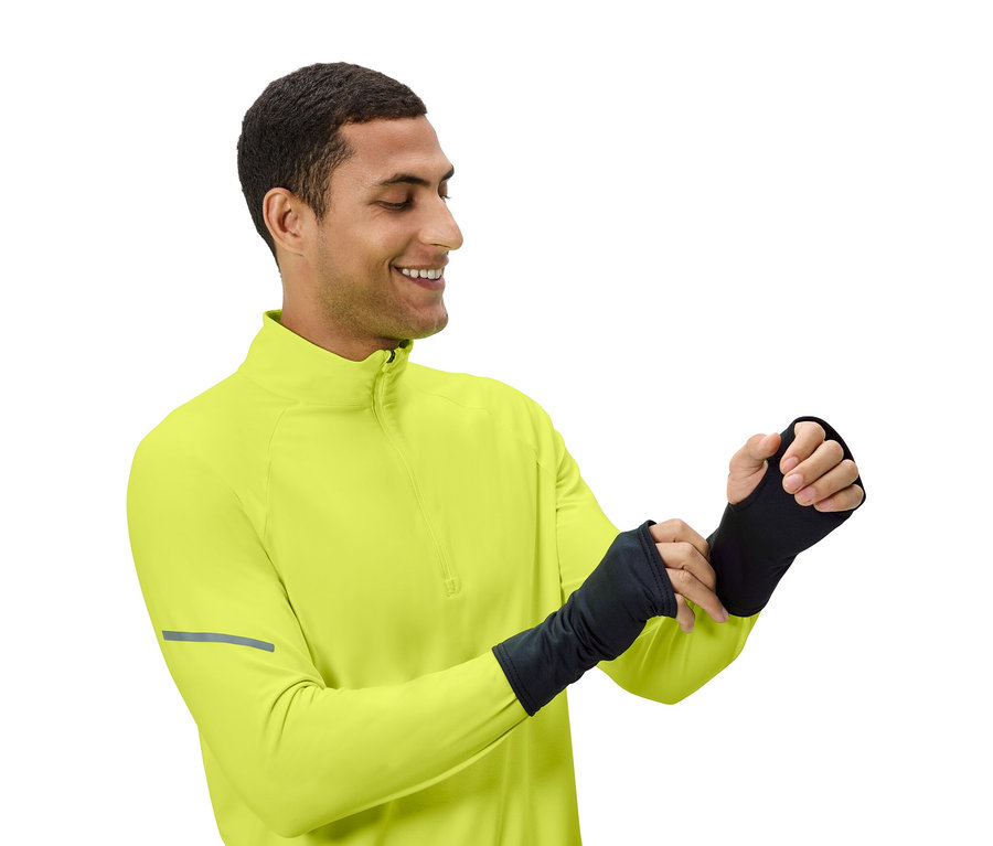 Mężczyzna poprawia czarne rękawiczki bez palców, ubrany w żółto-zieloną bluzę.