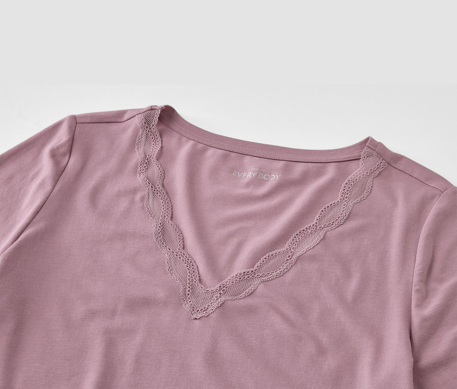 Szczegół fioletowej koszulki z dekoltem w serek i koronką.